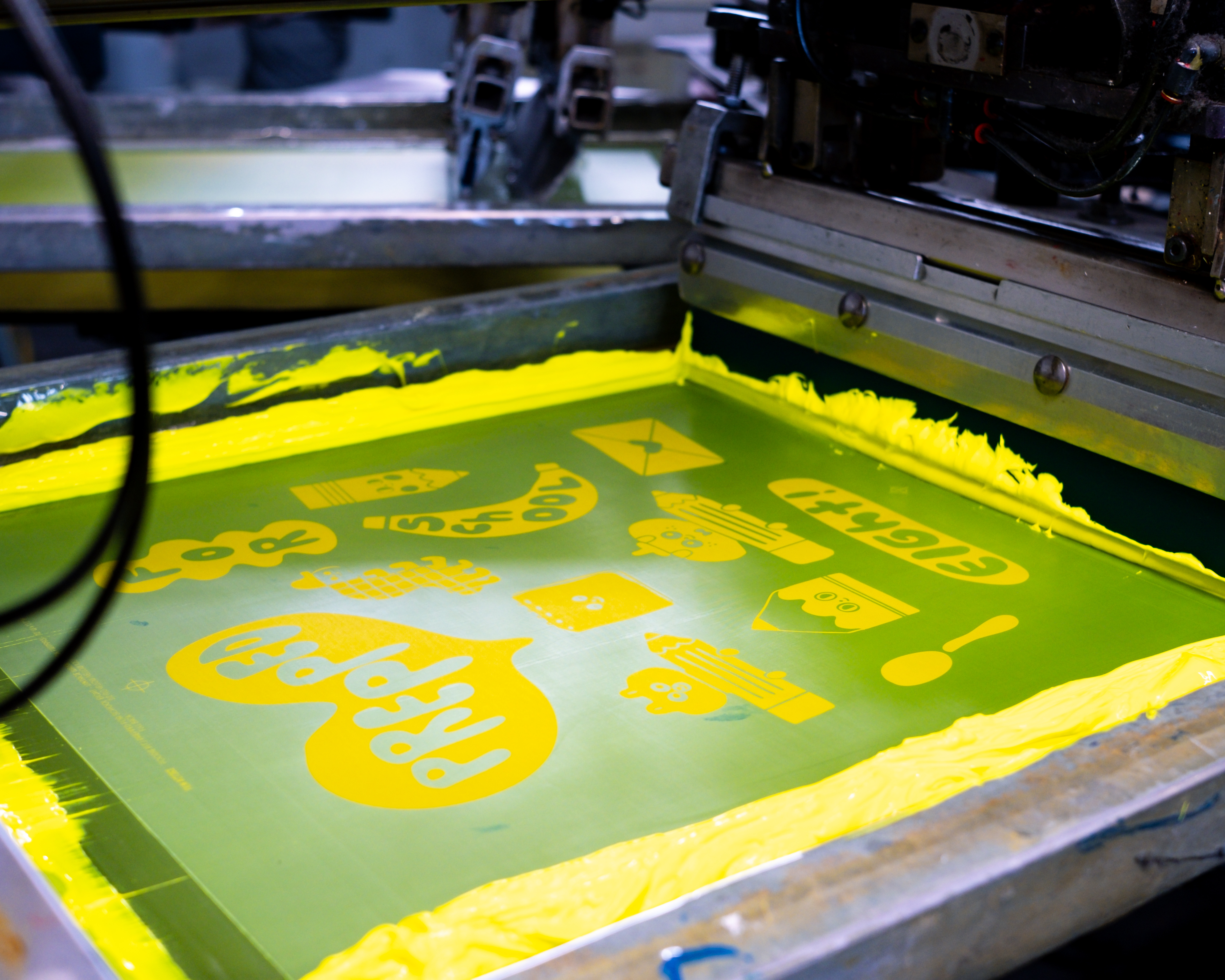 Screen printing press applying yellow ink to a design